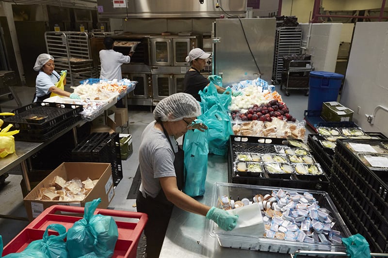 meals on wheels employees packing food in warehouse to distribute