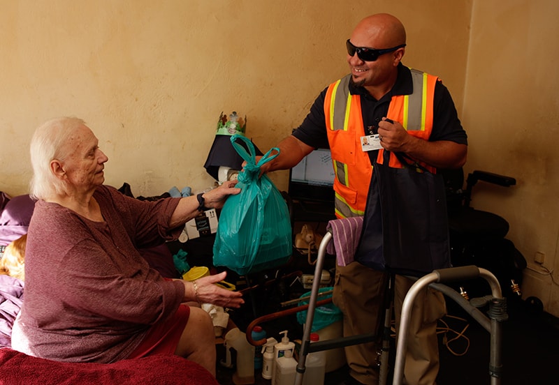 meals on wheels employee handing elderly woman bag of food