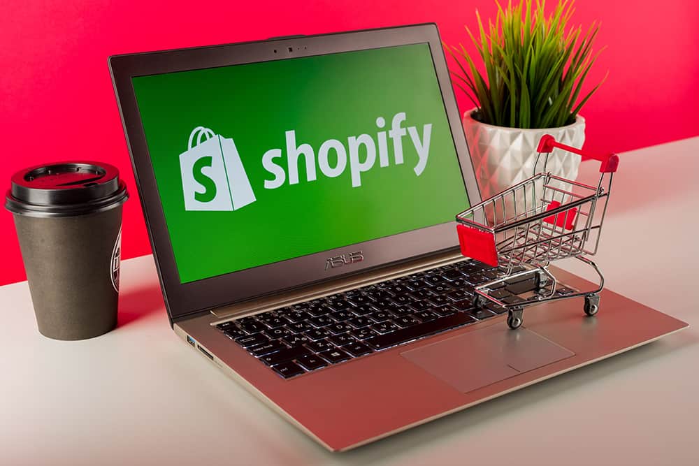 An image of a the Shopify logo on a latptop with inventory management strategies implied.