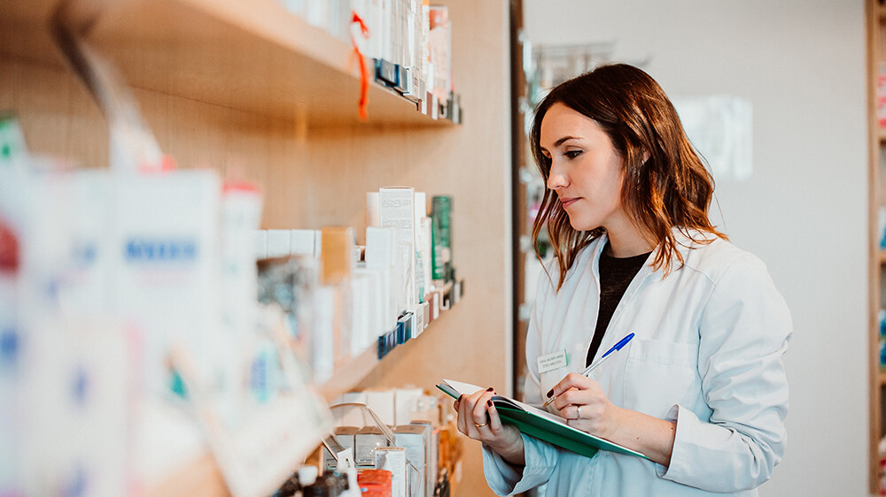 A young female pharmacy worker manually checking her stock. Comparing numbers manually with a medical inventory management system is a good way to ensure proper counts.