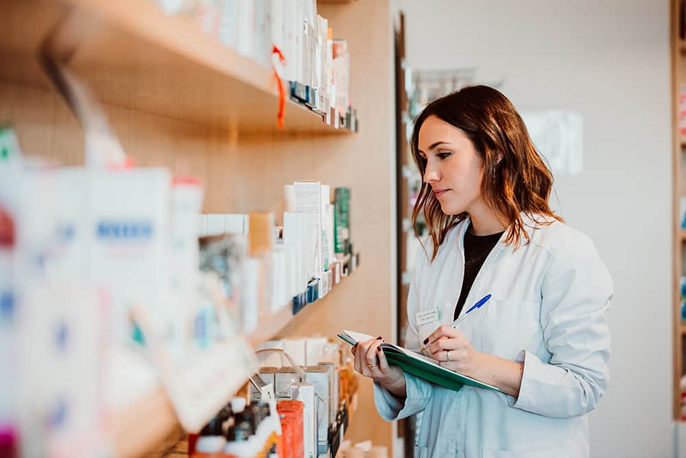 A young female pharmacy worker manually checking her stock. Comparing numbers manually with a medical inventory management system is a good way to ensure proper counts.