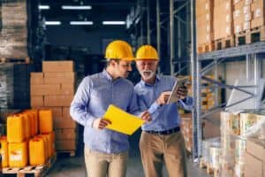 management reviewing inventory in warehouse on tablet