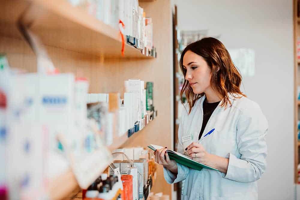 female pharmacy worker manually checking her consumable inventory and comparing numbers manually with a medical inventory management system